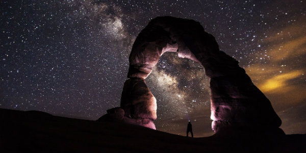 Stars in the night sky behind the silhouette of a stone arch