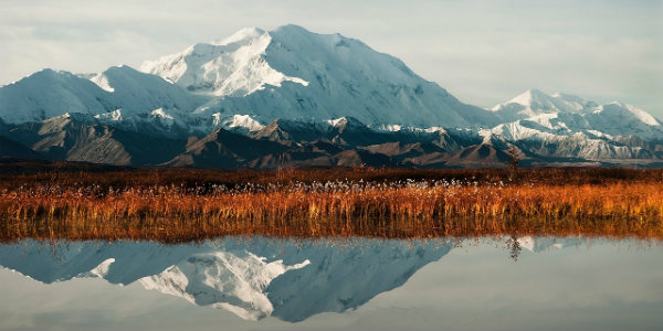 Clear lake water reflects snowcapped mountain peaks