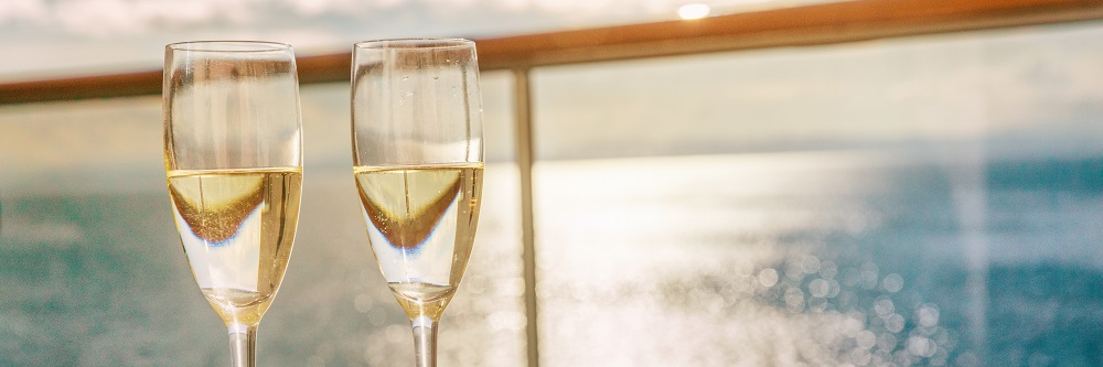 Luxury Cruise Ship Travel Champagne Glasses On Balcony Deck With Ocean Sunset View On Caribbean Vacation. Drinks In Sun Flare On Cruise Holiday Destination.