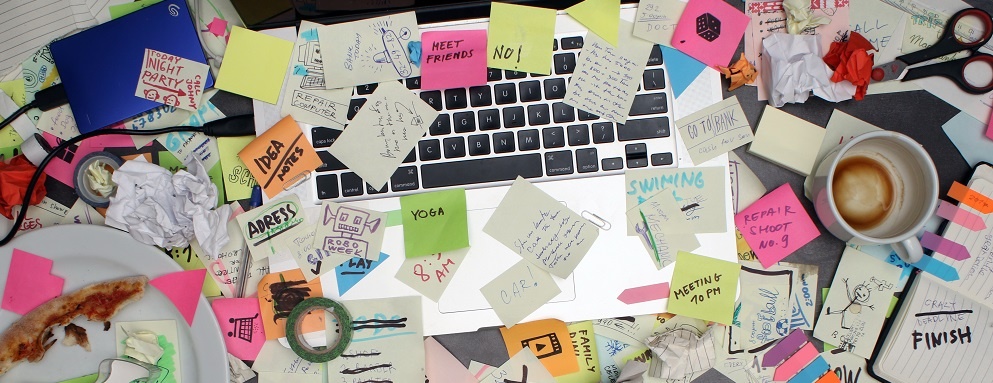 Top View On Office Desk With Laptop Computer And Post It Notes All Around. Overwhelmed With Work Concept.
