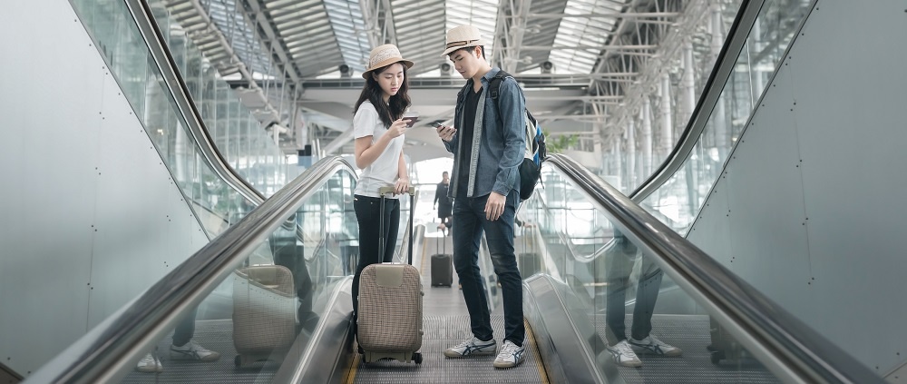 Young Asian Couple With Luggage Down The Escalator In Airport Travel