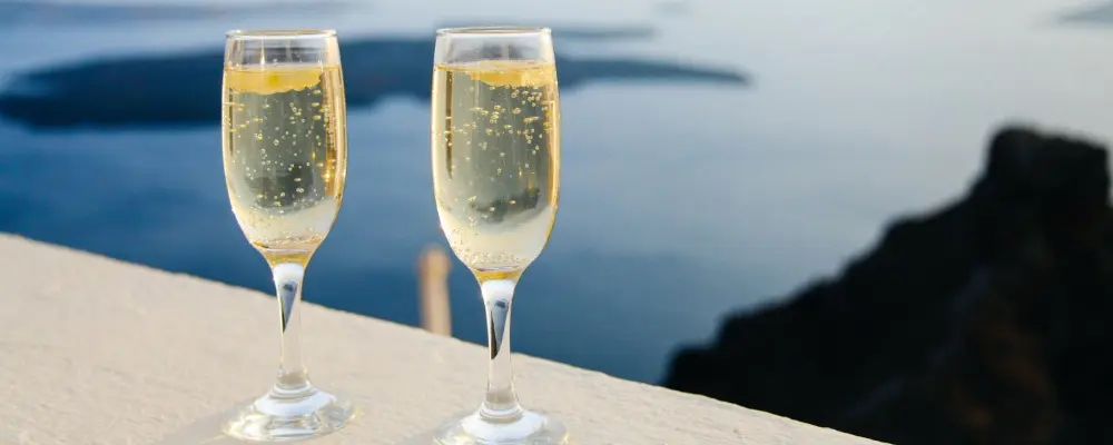 Two glasses of champagne on the edge of a balcony with an ocean backdrop