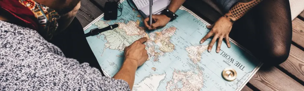 Two travelers examine a world map