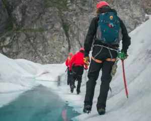 3 hikers trekking next to a frozen stream