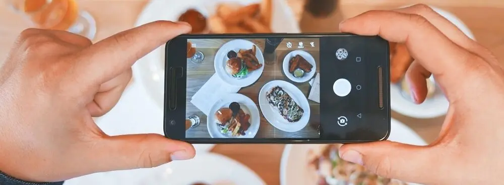 Cell phone taking a photo of restaurant dishes