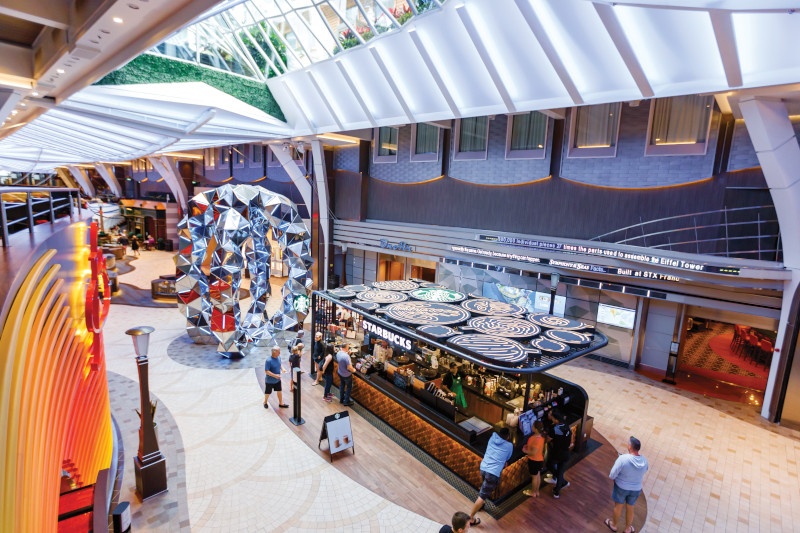 Overhead view of Starbucks cafe on the Promenade, designs on roof, guests walking, ordering coffee, large sculpture, artwork, art, On Air in background, Central Park seen through skylights above, Symphony of the Seas