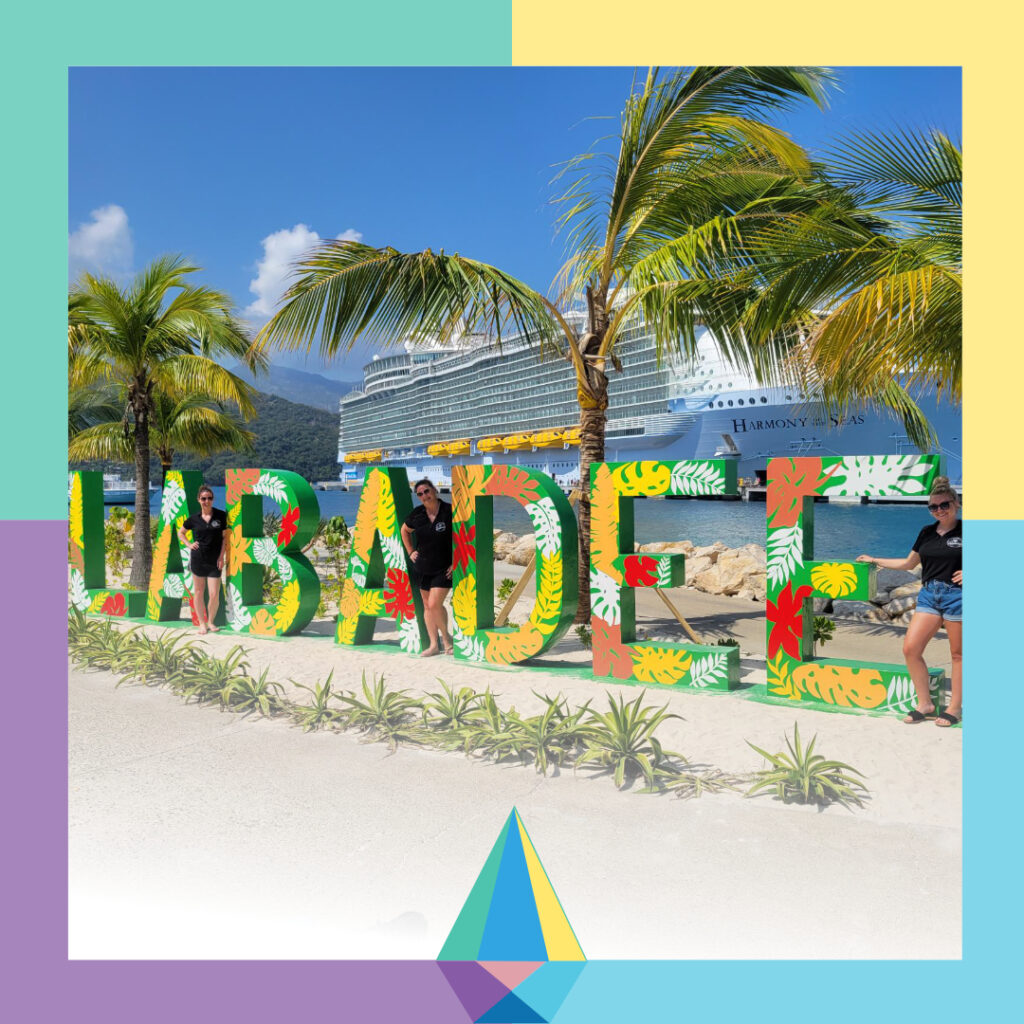 Three women posing in front of colorful Labadee sign in port with Crystal Conference logo at the bottom of the image