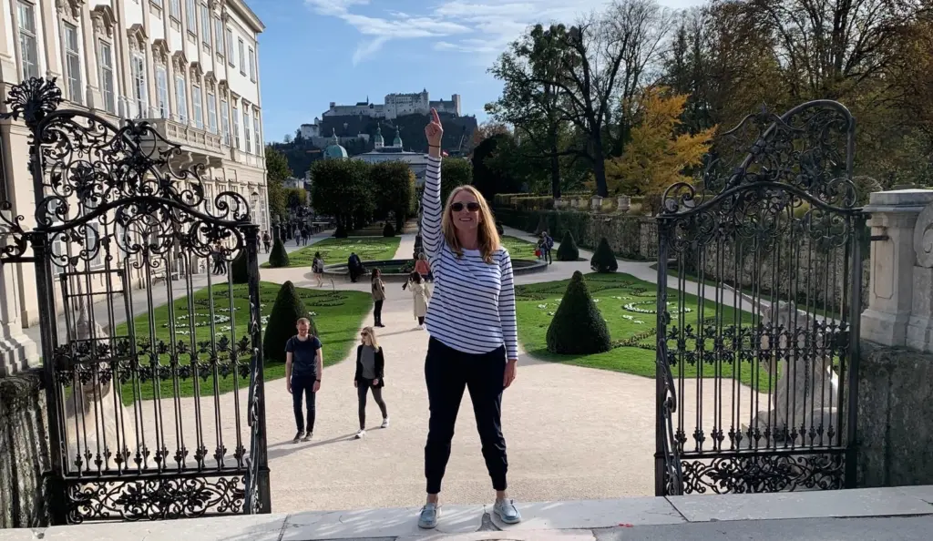 Woman standing in European courtyard pointing to the castle behind her