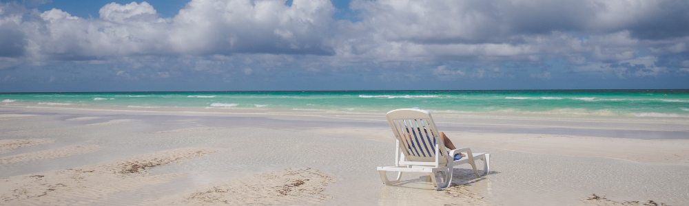 wide sandy beach with sea facing beach chair with turquoise water in the background
