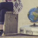 Person Sitting Next To Suitcase Globe